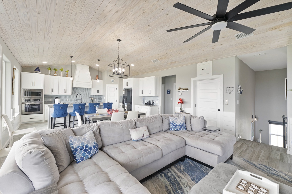 Relax on your plush sectional sofa while the coastal breeze flows through your spacious open-plan living area with modern kitchen.