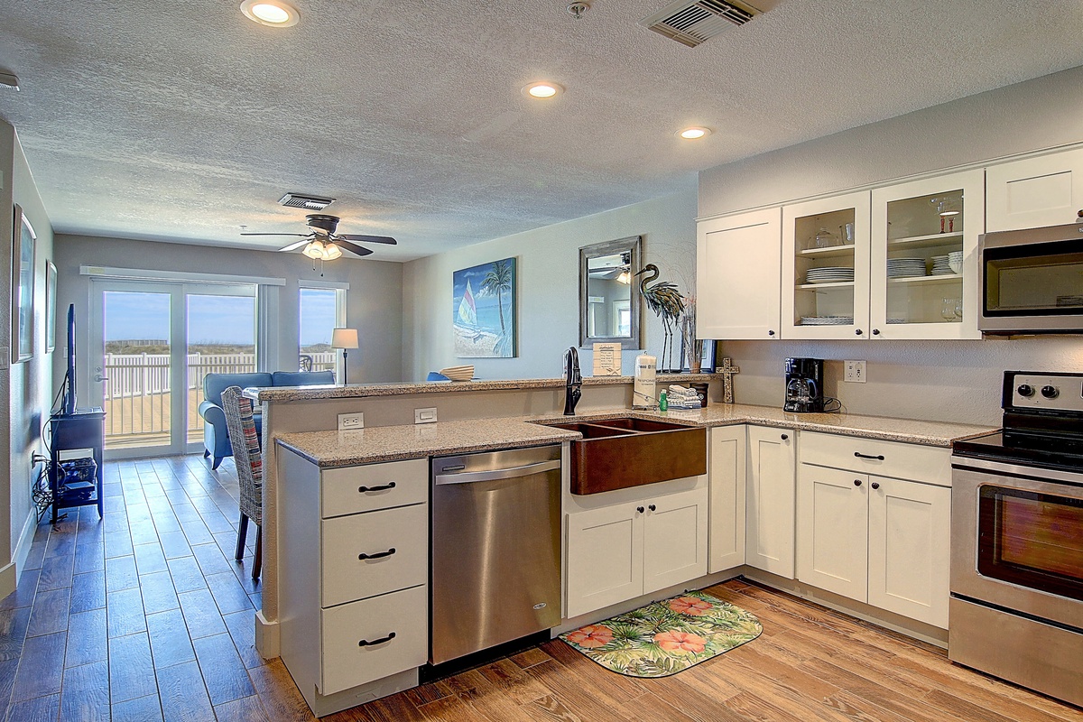 Your fully equipped kitchen flows seamlessly into the living area, perfect for preparing meals while enjoying ocean views through expansive windows.