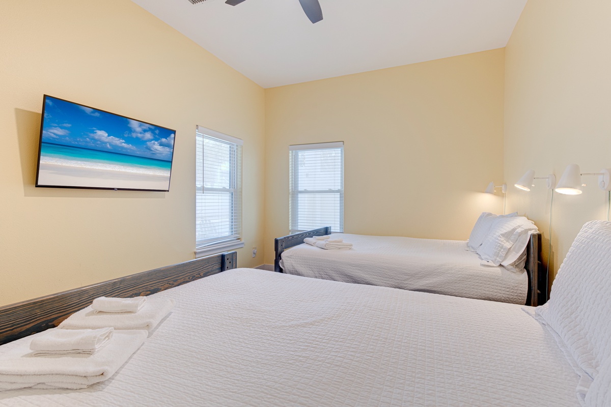 Unwind in your bright twin bedroom with crisp linens and a large TV displaying tropical beach scenes to set your vacation mood.