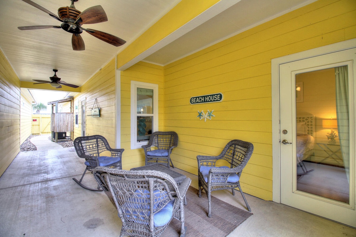 Relax in your private covered porch with coastal charm - wicker seating and ceiling fans create the perfect spot to unwind.