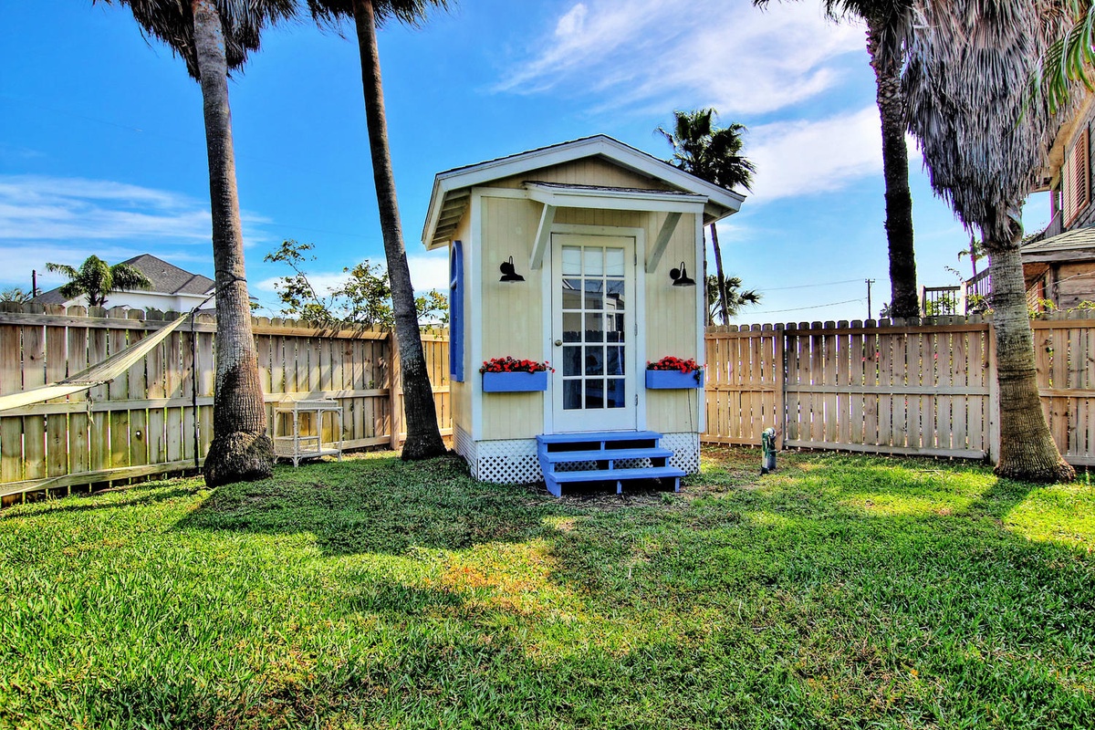 Charming coastal cottage with palm trees creating your perfect tropical getaway in a peaceful, fenced yard.