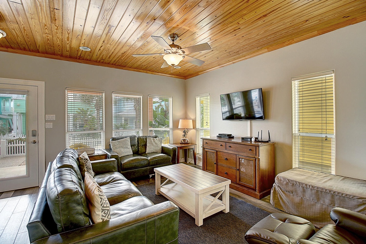 Unwind in your spacious living room featuring rich leather seating, stunning wood-planked ceilings, and modern entertainment setup for perfect relaxation.