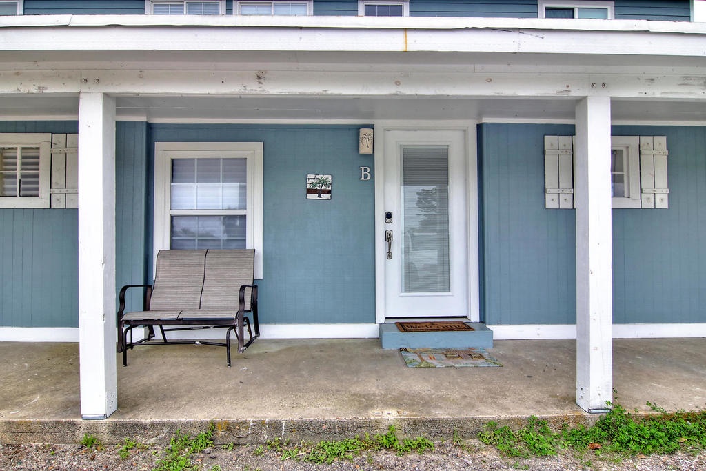 Welcoming entrance to your seaside retreat with covered porch seating and charming coastal blue exterior.
