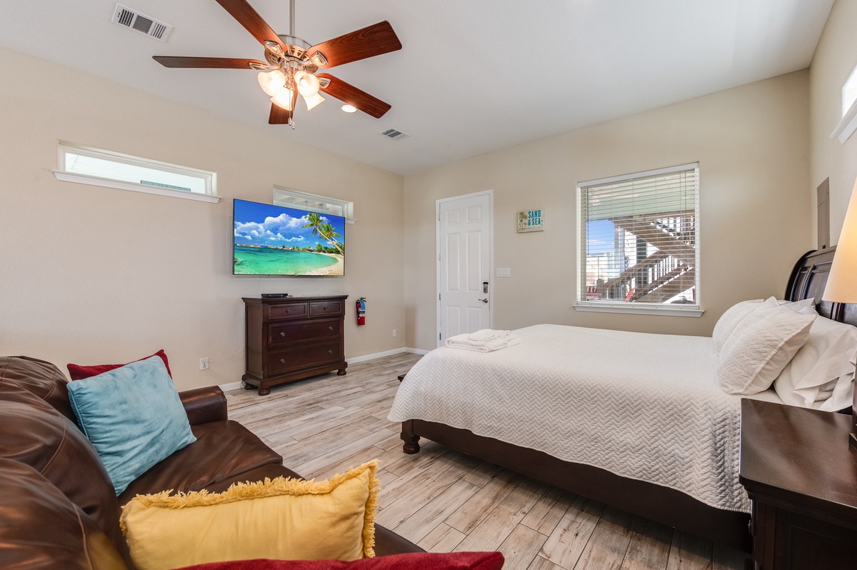 Unwind in this cozy bedroom where soft linens meet comfortable seating. The ceiling fan keeps you cool while you relax.