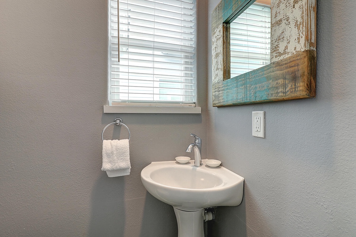 Freshen up in your bright powder room featuring soft natural light and coastal-inspired touches.