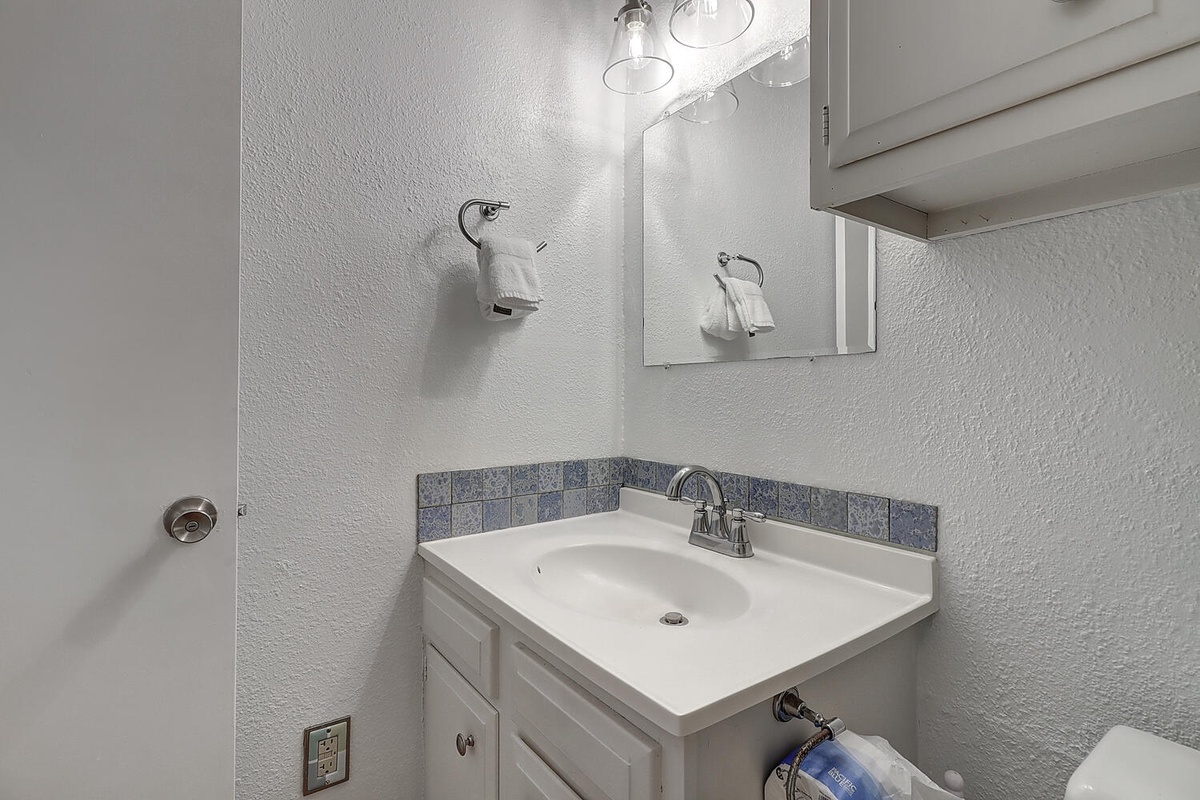 Freshen up in your private bathroom featuring a spacious vanity with ample storage and charming blue tile accents.