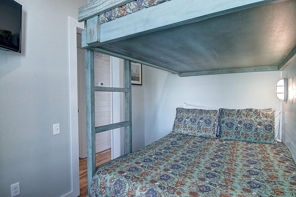 Your unique bedroom features charming rustic beams and a cozy queen bed with intricate patterns, creating a serene retreat for peaceful nights.