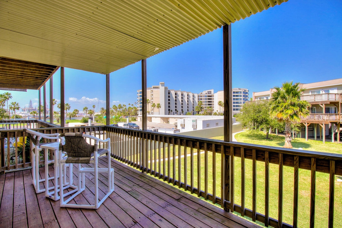 Step onto your private covered balcony and unwind in comfortable seating while taking in expansive city views under brilliant blue skies.