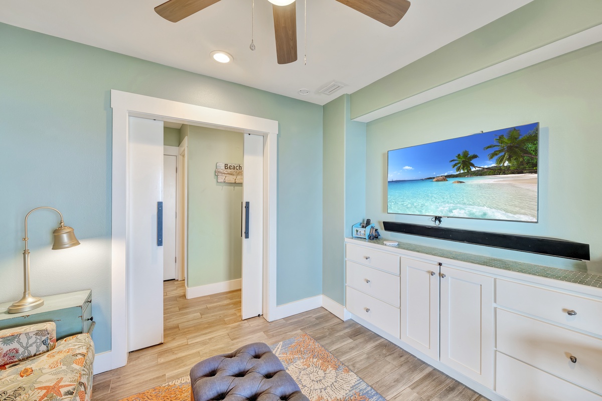 Sink into coastal bliss in your bright living space, where soothing sea-green walls and tropical beach scenes create pure vacation magic.