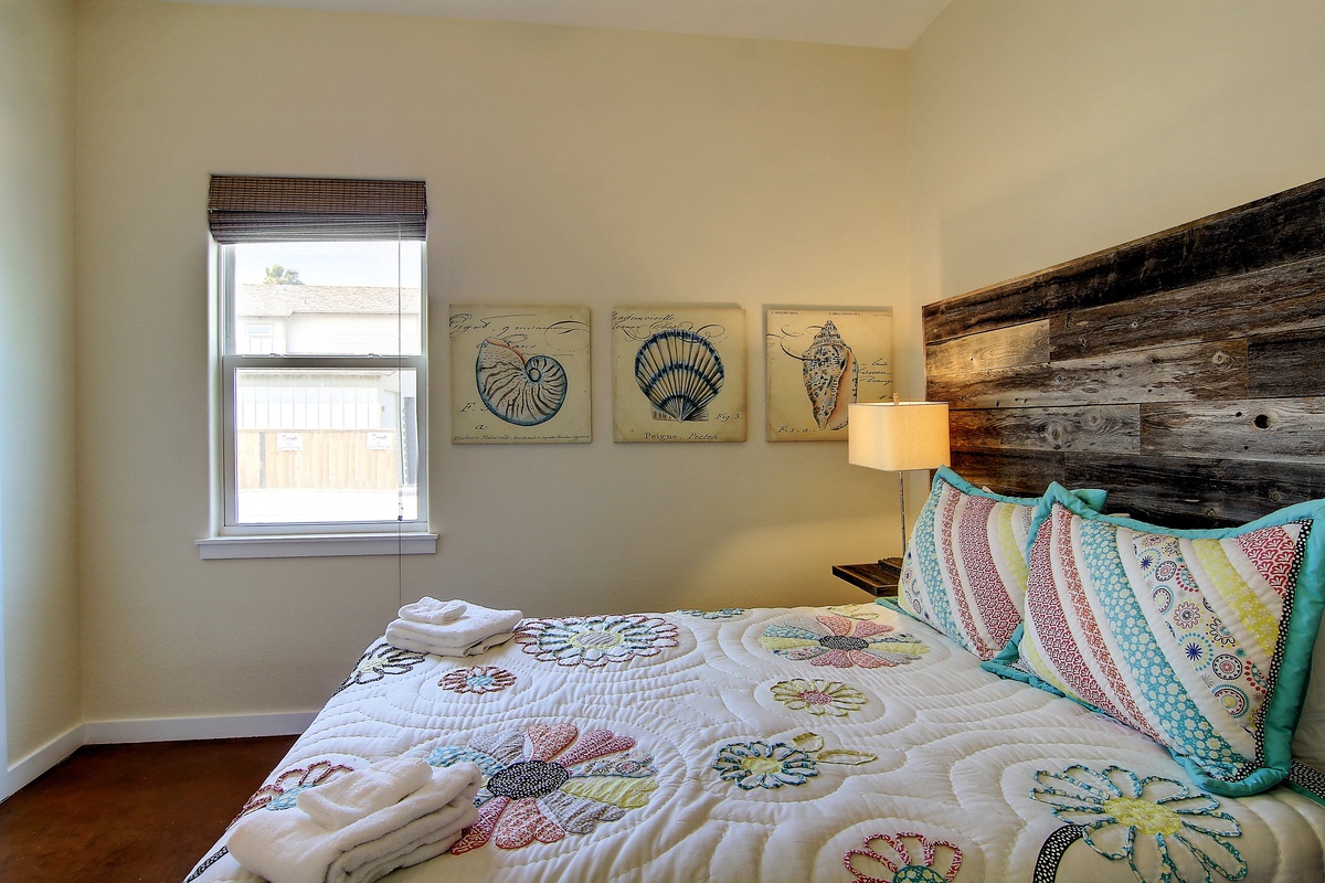 Drift into peaceful sleep in your coastal-themed bedroom, where reclaimed wood headboard meets cheerful nautical art and soft quilted bedding.