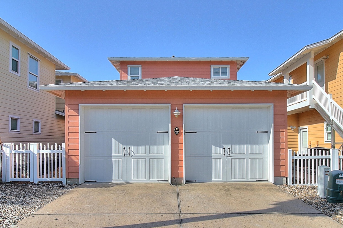 Charming coral-colored beach house with convenient two-car garage parking in a peaceful coastal neighborhood.