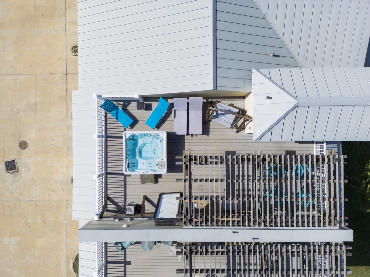 Aerial view of vacation rental deck featuring hot tub, lounge furniture and outdoor relaxation space surrounded by white railings.