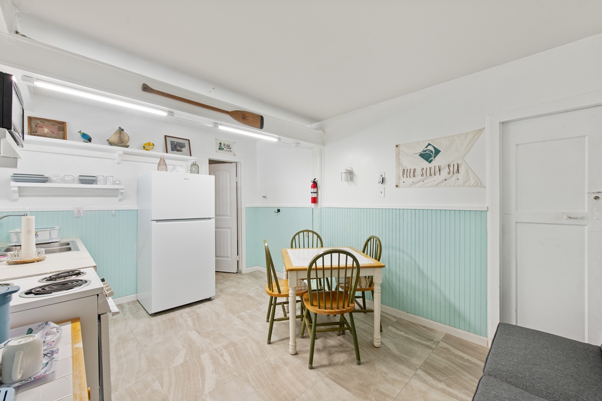 Your coastal-themed kitchen and dining nook features charming mint wainscoting, rustic beamed ceilings, and nautical touches that create the perfect seaside retreat atmosphere.