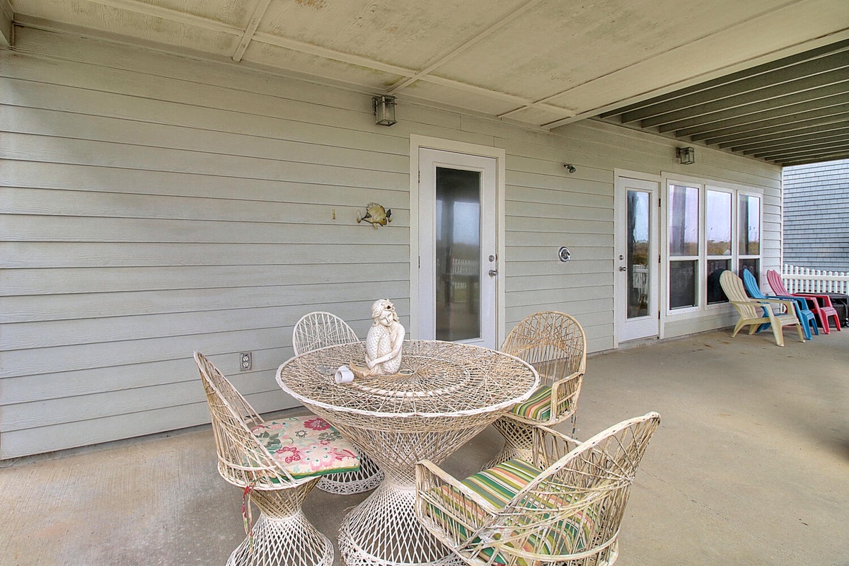 Your covered patio offers the perfect spot to gather with loved ones around this charming wicker dining set, complete with colorful cushions for comfort.