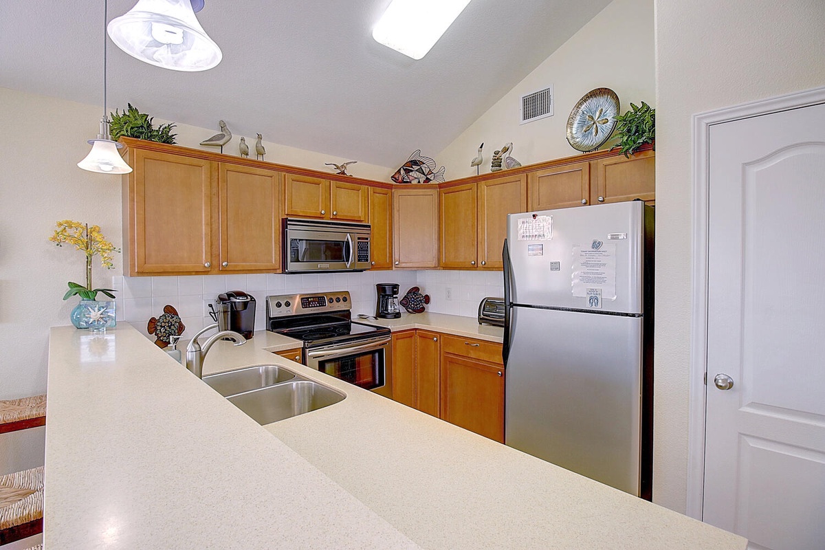 Your fully-equipped kitchen offers everything needed for home cooking, with warm wood cabinets and modern appliances creating a welcoming space for preparing meals.