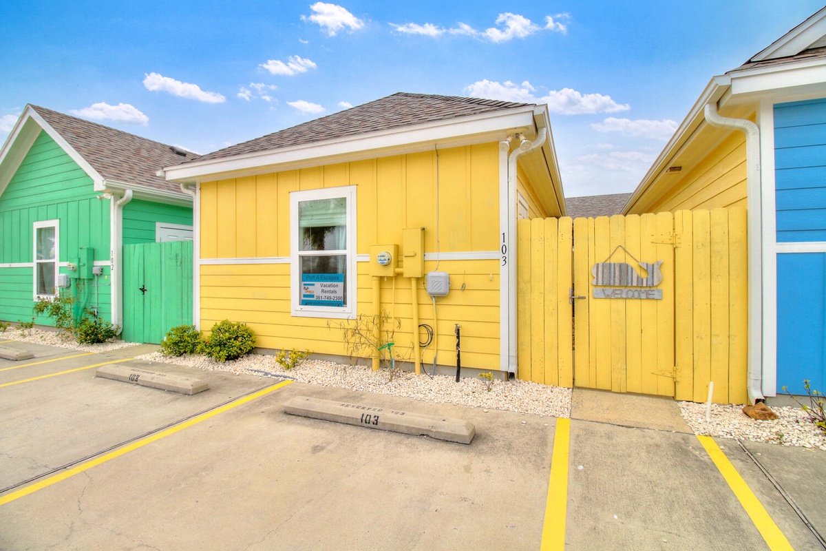 Colorful beachside cottages with dedicated parking spaces create a vibrant coastal community setting.