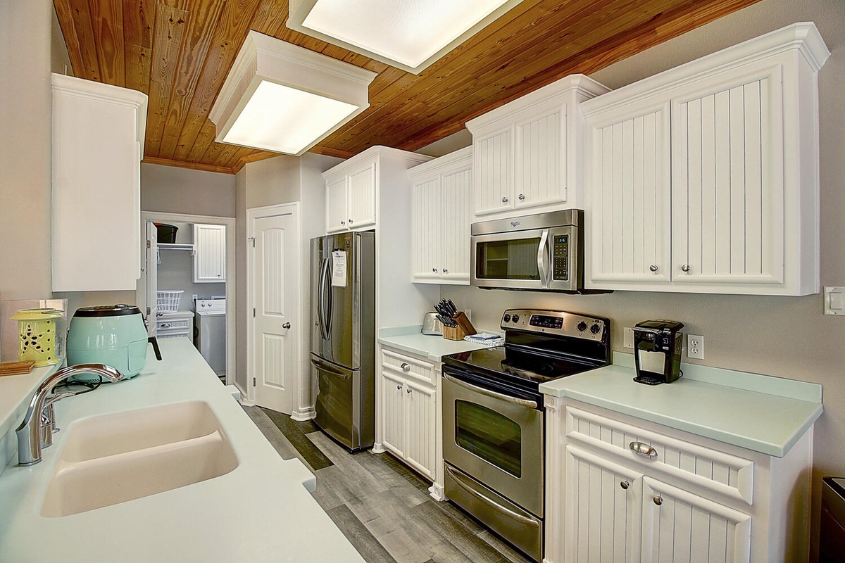 Your fully equipped kitchen features white cabinets, stainless appliances, and charming exposed beams overhead—perfect for preparing meals with style and comfort.