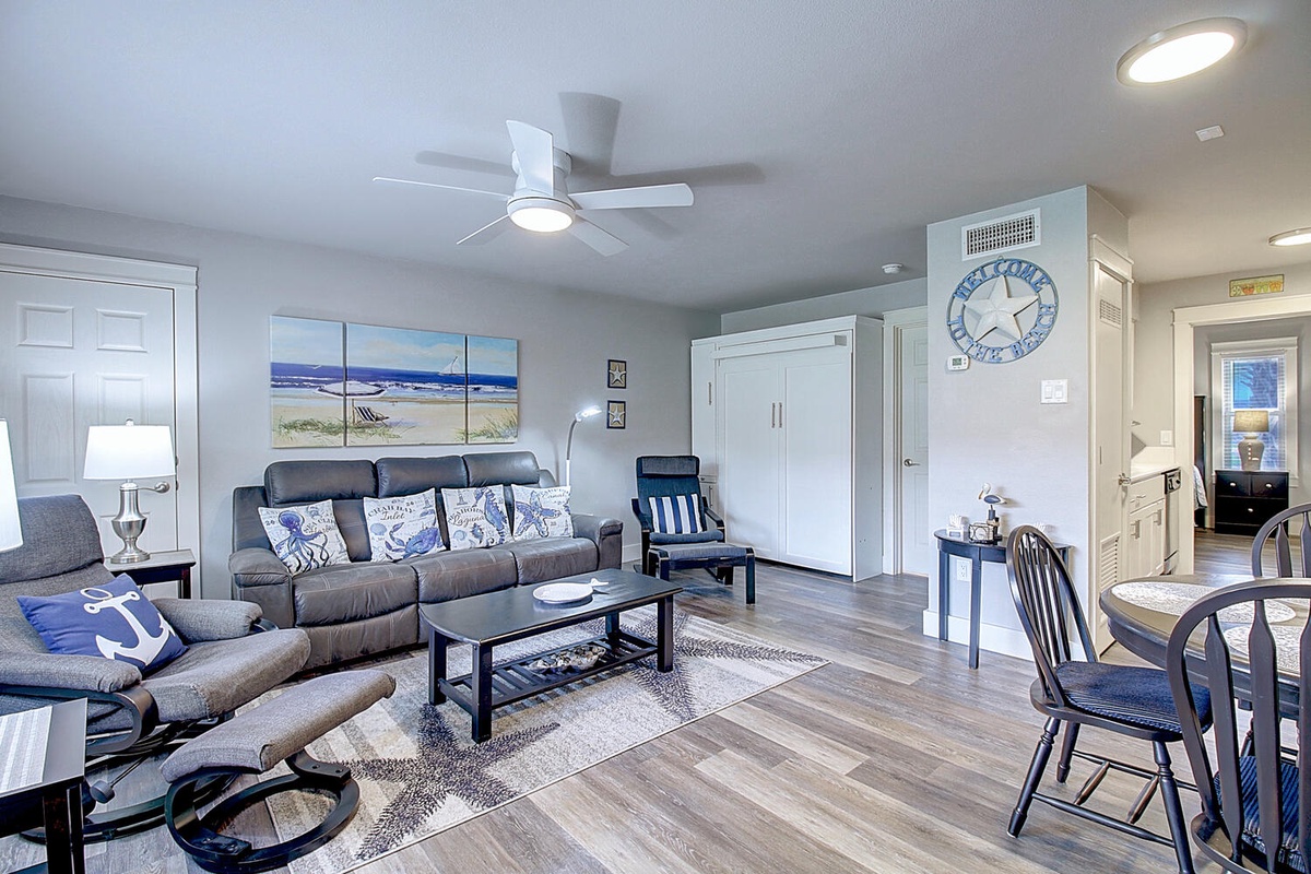 Relax in your coastal-themed living space with nautical décor, comfortable seating, and a ceiling fan for perfect comfort.