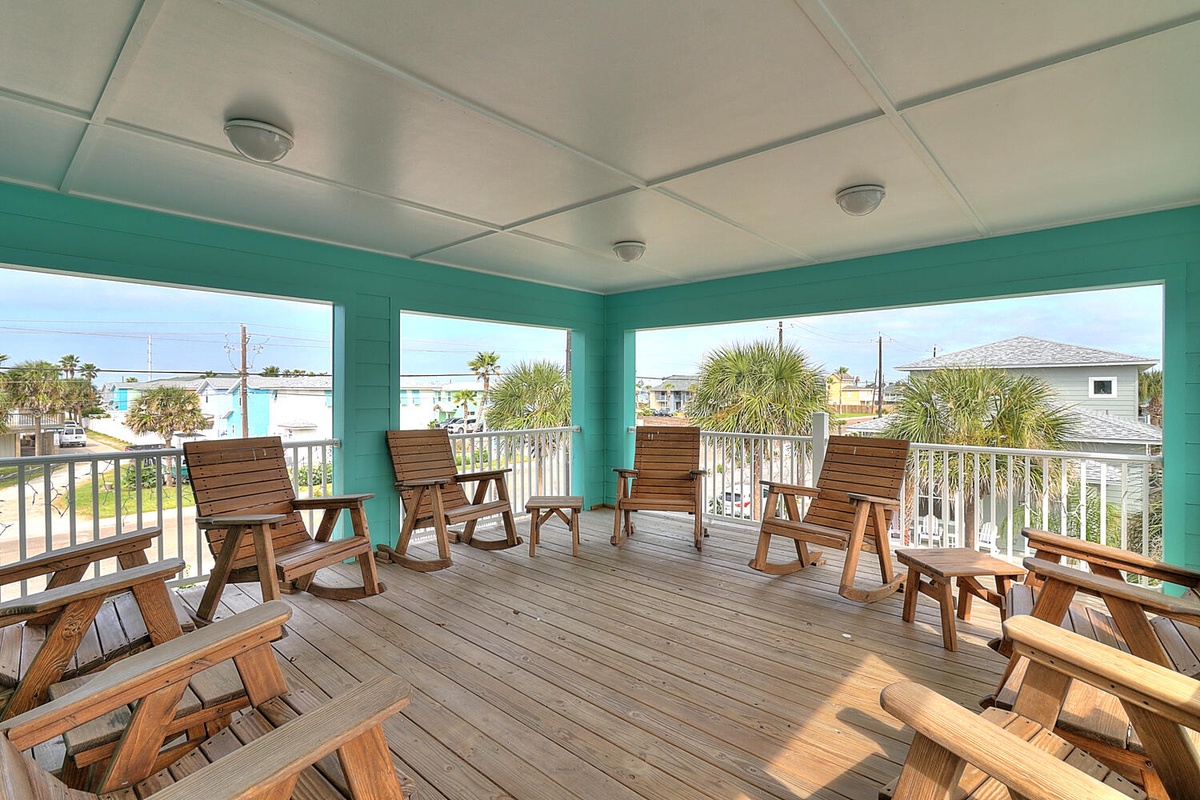 Unwind in your private screened balcony with comfortable wooden seating, where tropical breezes and palm tree views create the perfect spot for morning coffee.