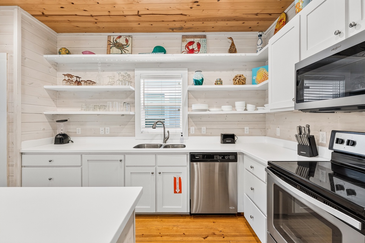 Bright, well-equipped kitchen with crisp white cabinetry, open shelving, and plenty of space for preparing meals.