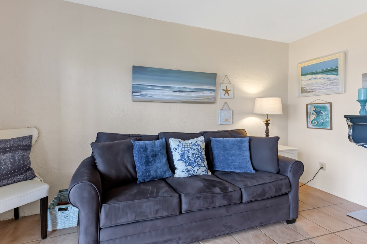 Sink into this coastal-themed living room where ocean artwork and soft blue accents create your peaceful retreat.