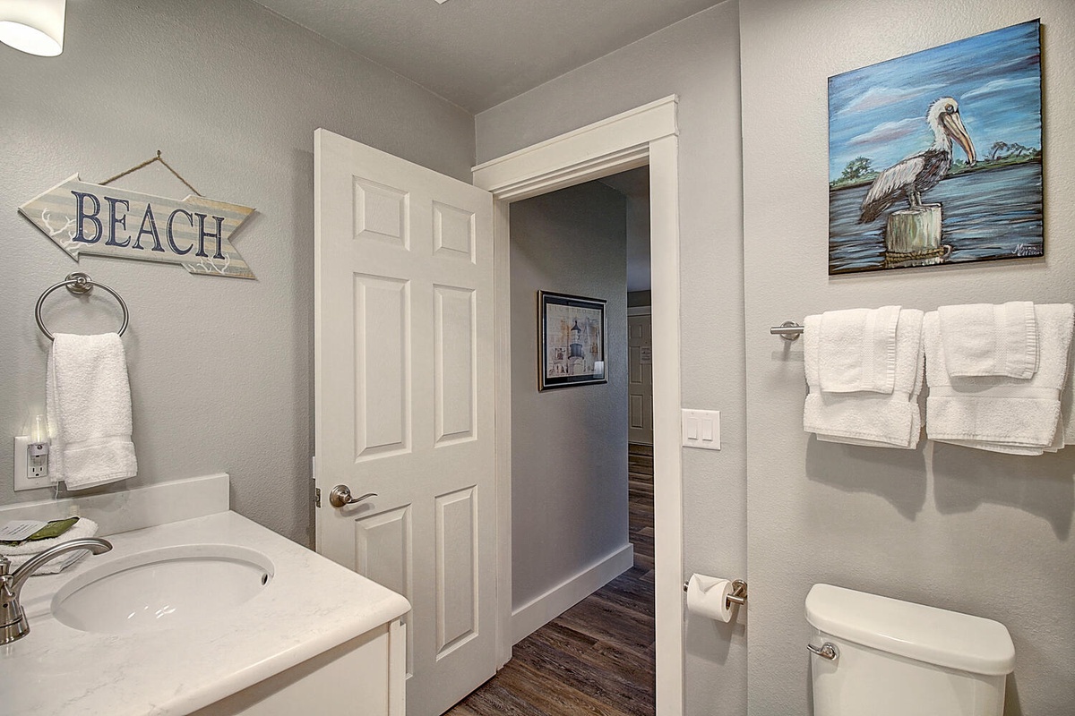 Refresh in your coastal-themed bathroom with soft towels and charming beach artwork that makes every morning feel like a seaside getaway.