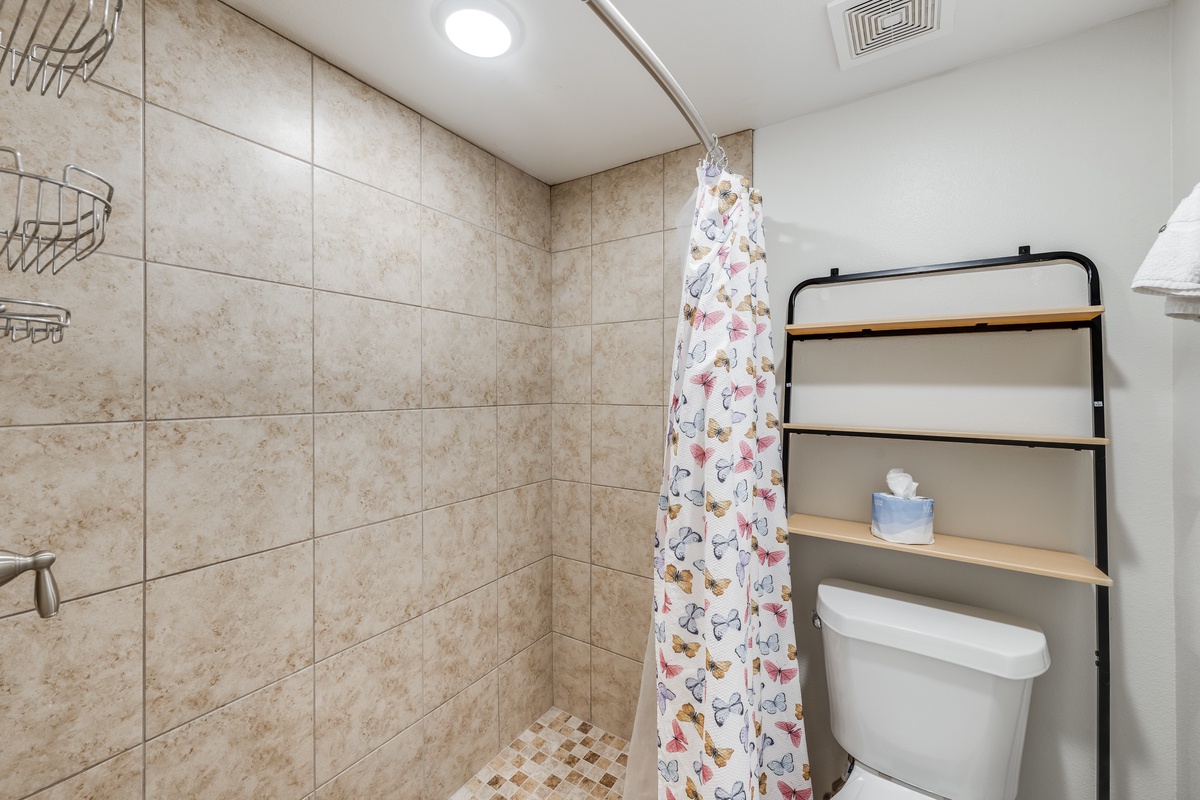 Step into your private bathroom with spacious tiled shower, convenient storage shelving, and thoughtful amenities for your comfort.