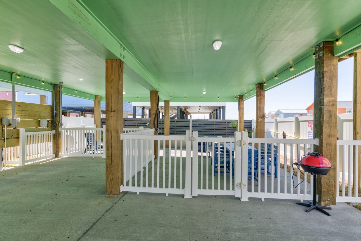Your covered porch offers shade and comfort with a charcoal grill ready for beachside barbecues after sunny days by the shore.