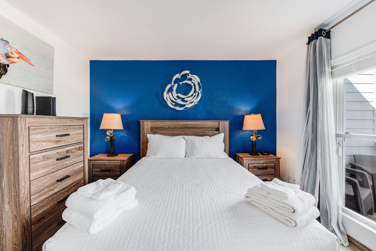 Step into your serene bedroom sanctuary with its striking navy accent wall and plush bedding waiting for restful nights.