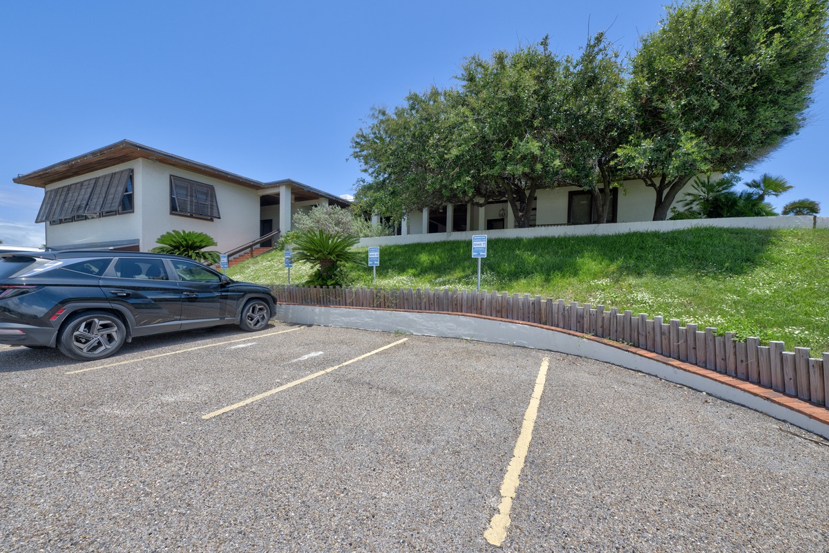 Modern beachside property with spacious parking and lush tropical landscaping under brilliant blue skies.
