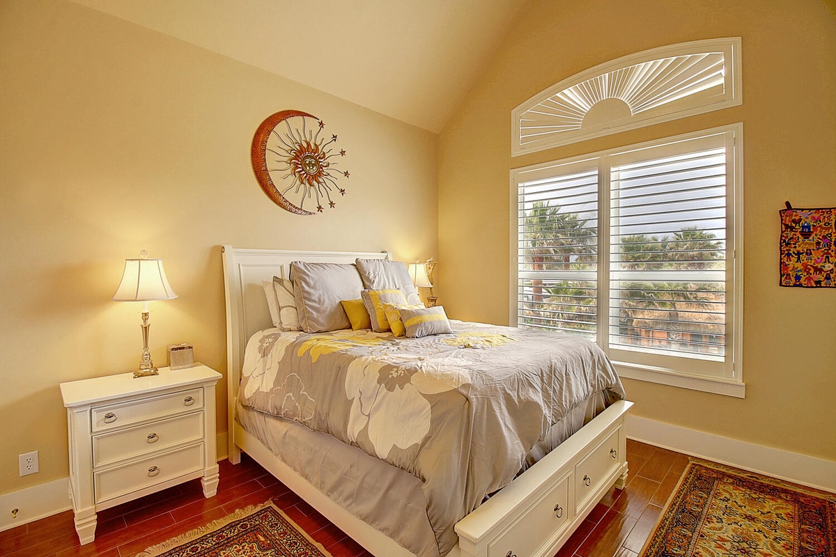 Sink into your cozy bedroom sanctuary with soft linens, warm golden walls, and peaceful tree views through elegant arched windows.
