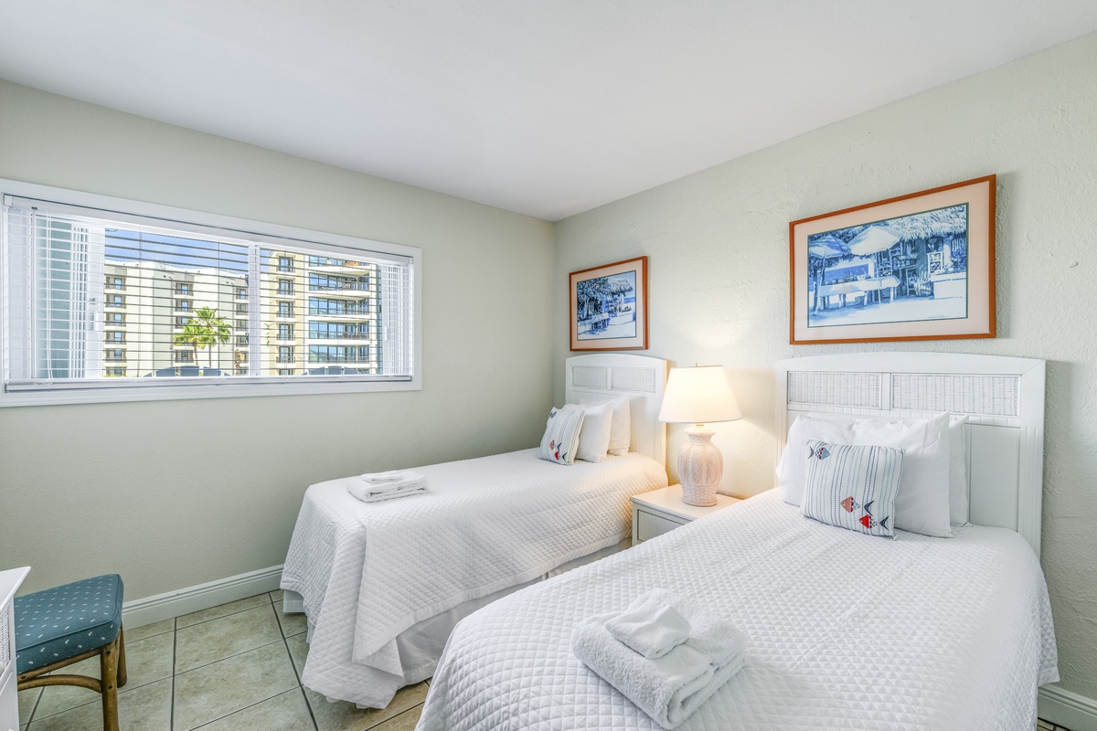 Drift off peacefully in crisp white linens while city lights twinkle beyond your window in this bright, serene twin bedroom.