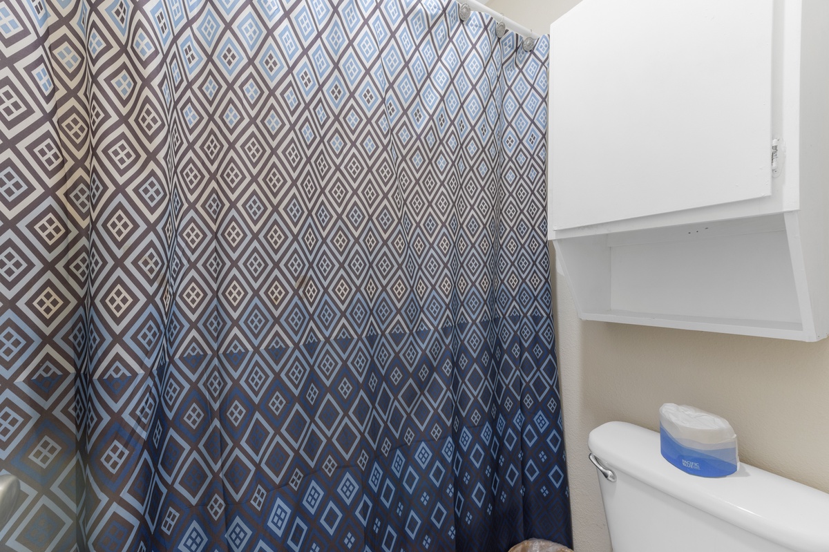 Step into your private bathroom featuring a stylish geometric shower curtain and modern fixtures for your comfort.