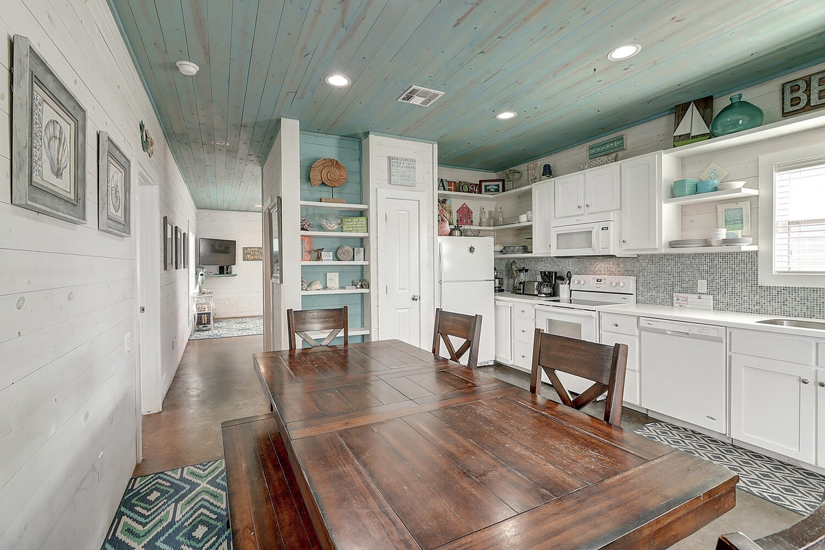 Your coastal kitchen and dining space features beautiful wood beam ceilings and a spacious table where you can gather for meals.