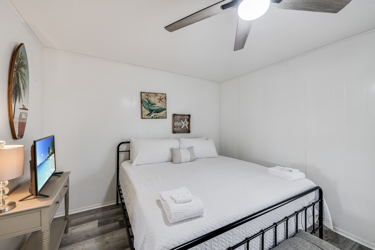 Unwind in this cozy bedroom featuring a comfortable queen bed, ceiling fan, and TV for your relaxation.