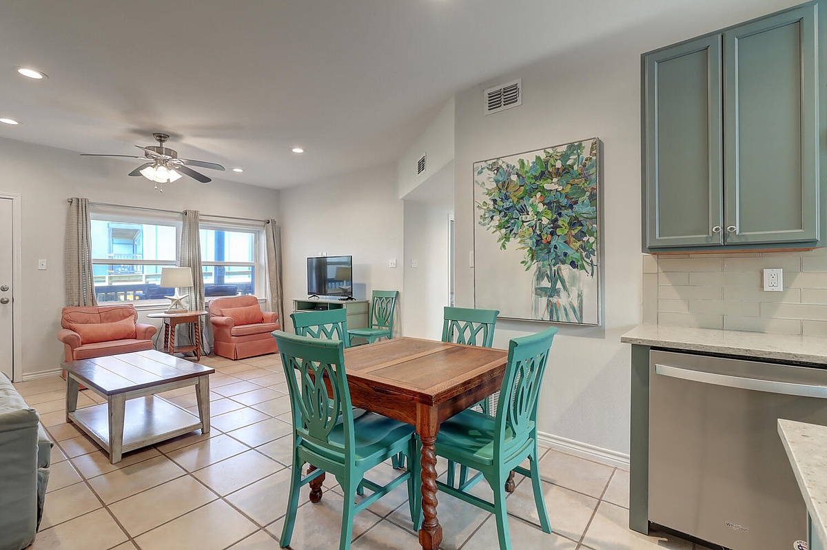 Relax in your bright open living space with charming turquoise dining chairs and coral accents that create a coastal vibe.