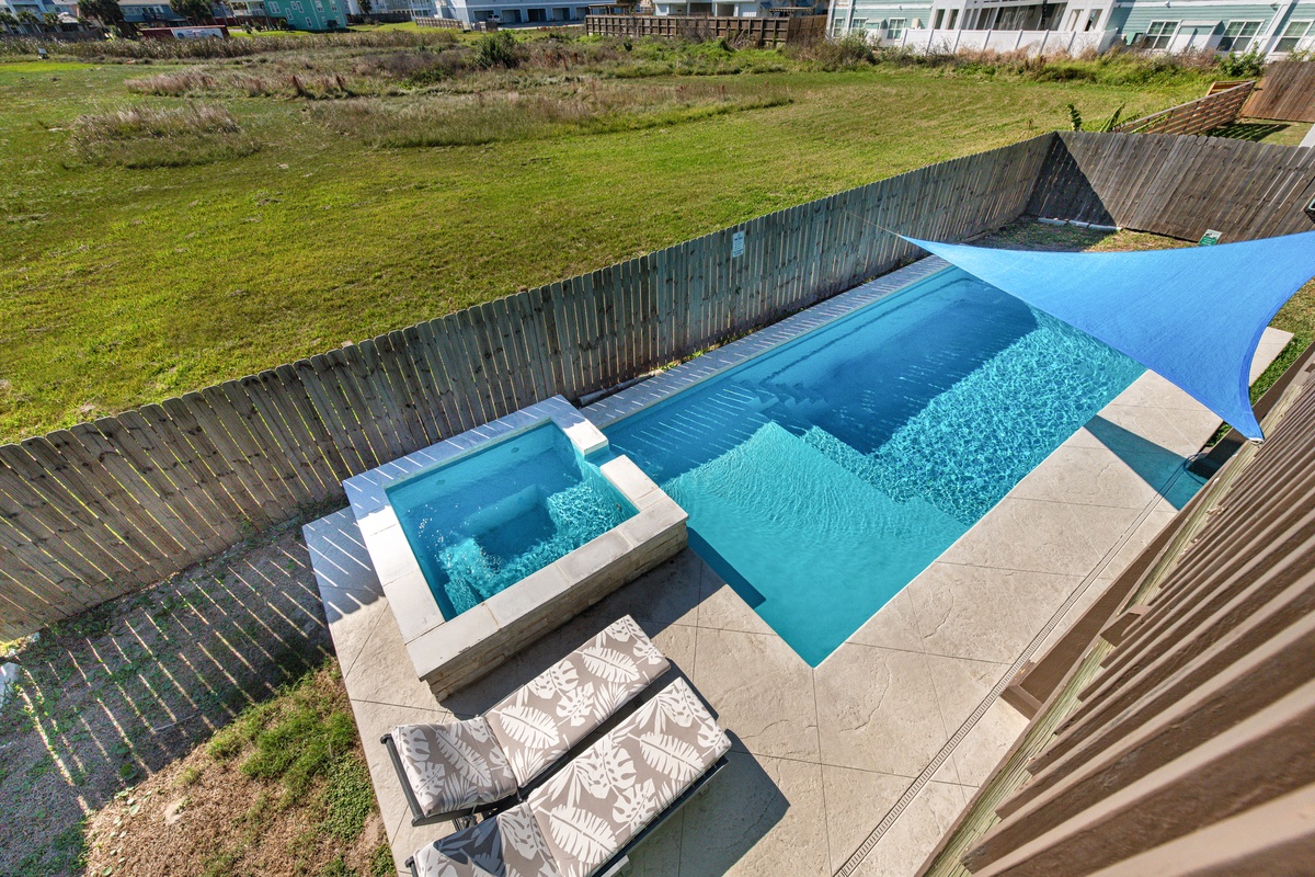 View from the balcony of the crystal-clear waters of your private pool and spa, complete with shade sail and loungers for ultimate relaxation.