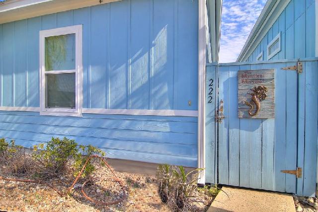 Charming beachside property with coastal blue siding and seahorse decor welcomes guests to their seaside retreat.