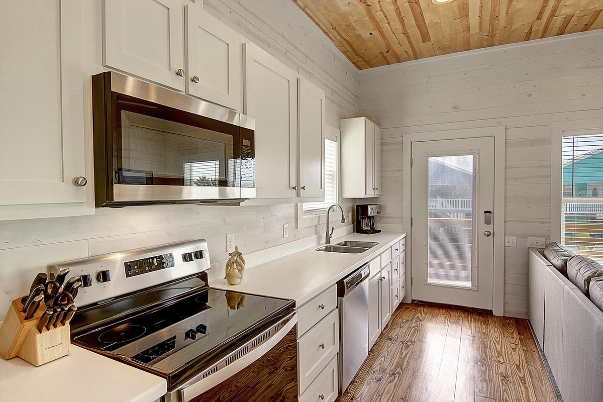 Cook your favorite meals in this bright, fully-equipped kitchen with modern appliances and charming wood ceiling details.
