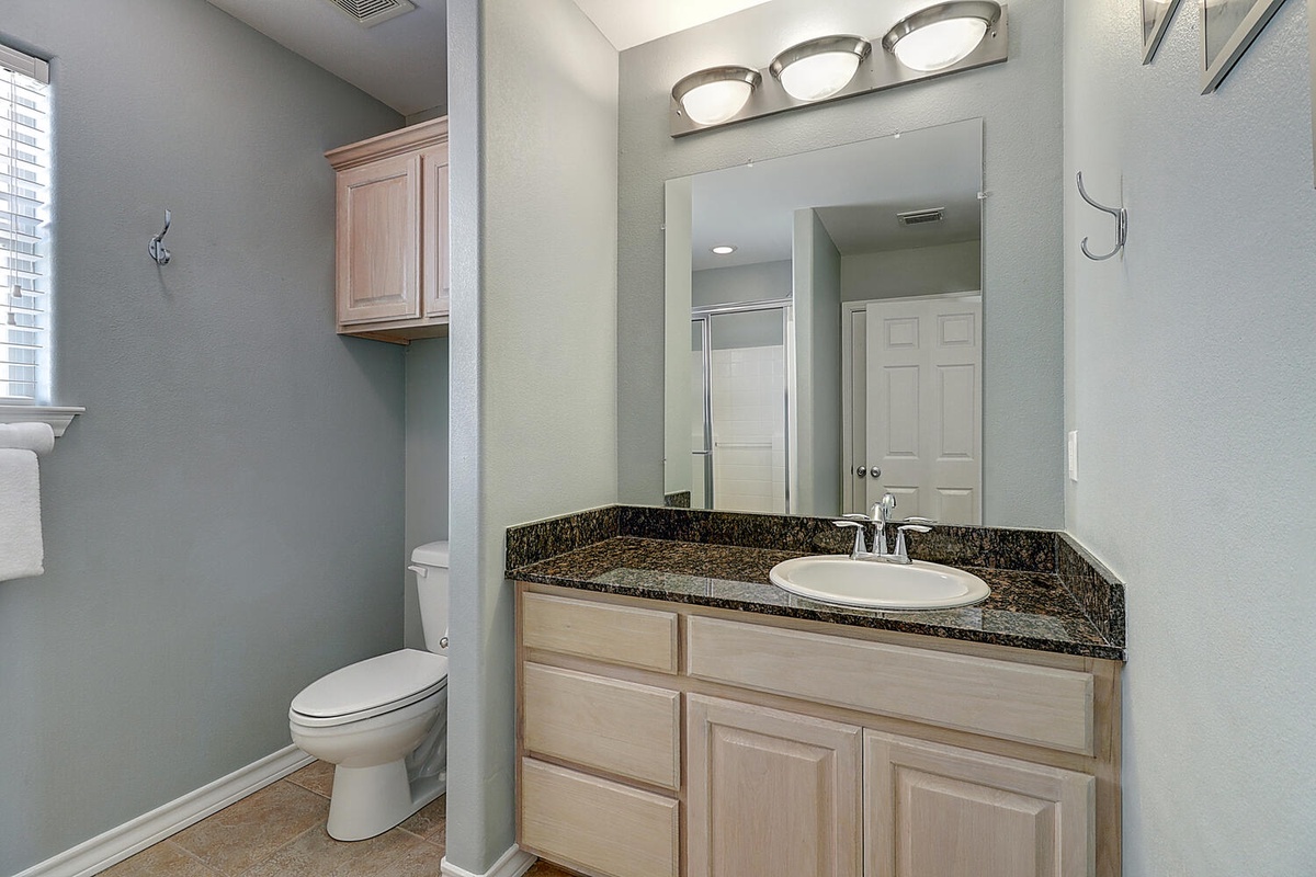 Freshen up in your private bathroom featuring elegant granite countertops, warm wood cabinetry, and modern fixtures for your comfort.