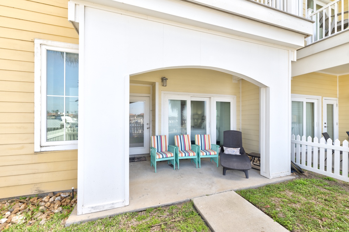 Unwind on your private covered patio with colorful striped seating and a cozy rocking chair, perfect for morning coffee or evening relaxation.