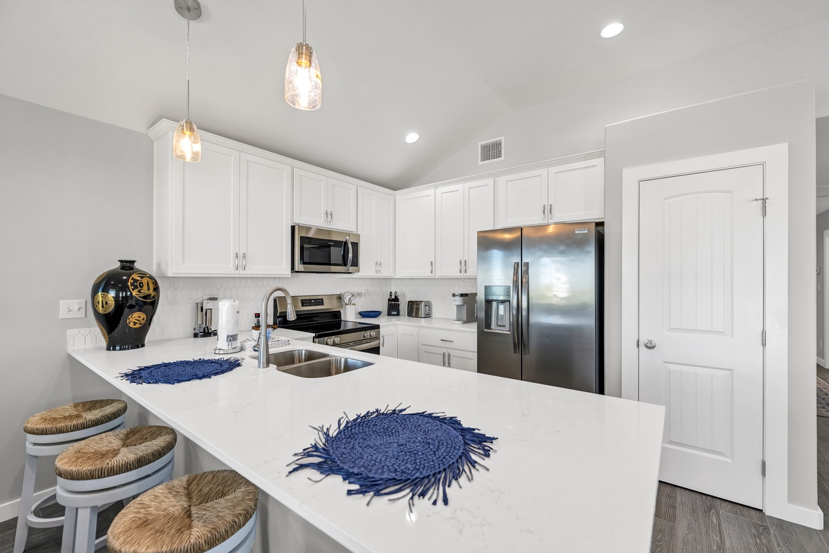 You'll love cooking in this bright modern kitchen with sparkling white cabinets, stainless appliances, and a spacious island perfect for morning coffee.