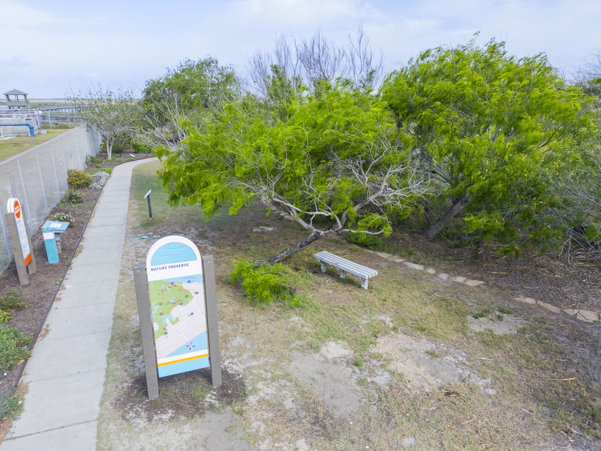 Nature preserve trail with walking path and interpretive signage surrounded by lush native vegetation and peaceful natural landscapes.
