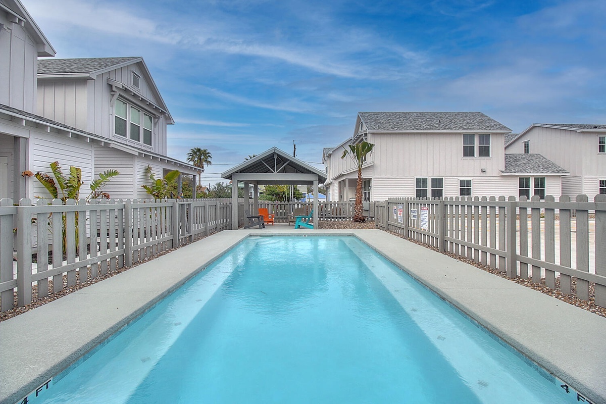 Dive into your private oasis with this pristine pool surrounded by charming coastal homes and tropical palms.