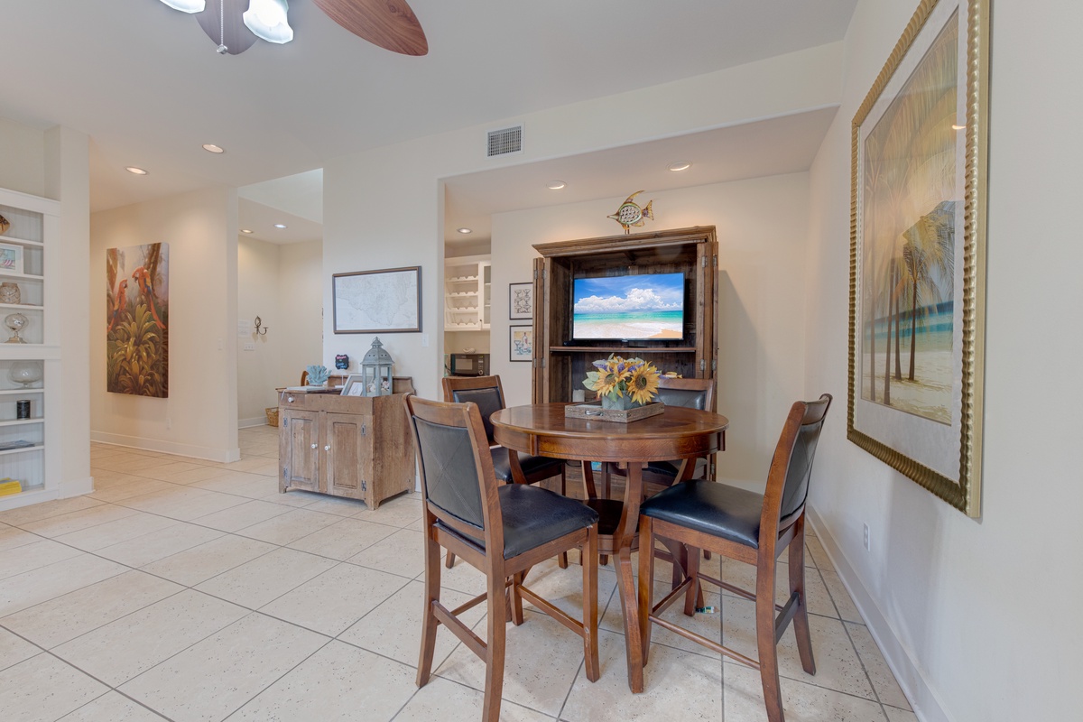 Your spacious dining area features rich wood furnishings and coastal artwork, perfect for memorable meals with loved ones.
