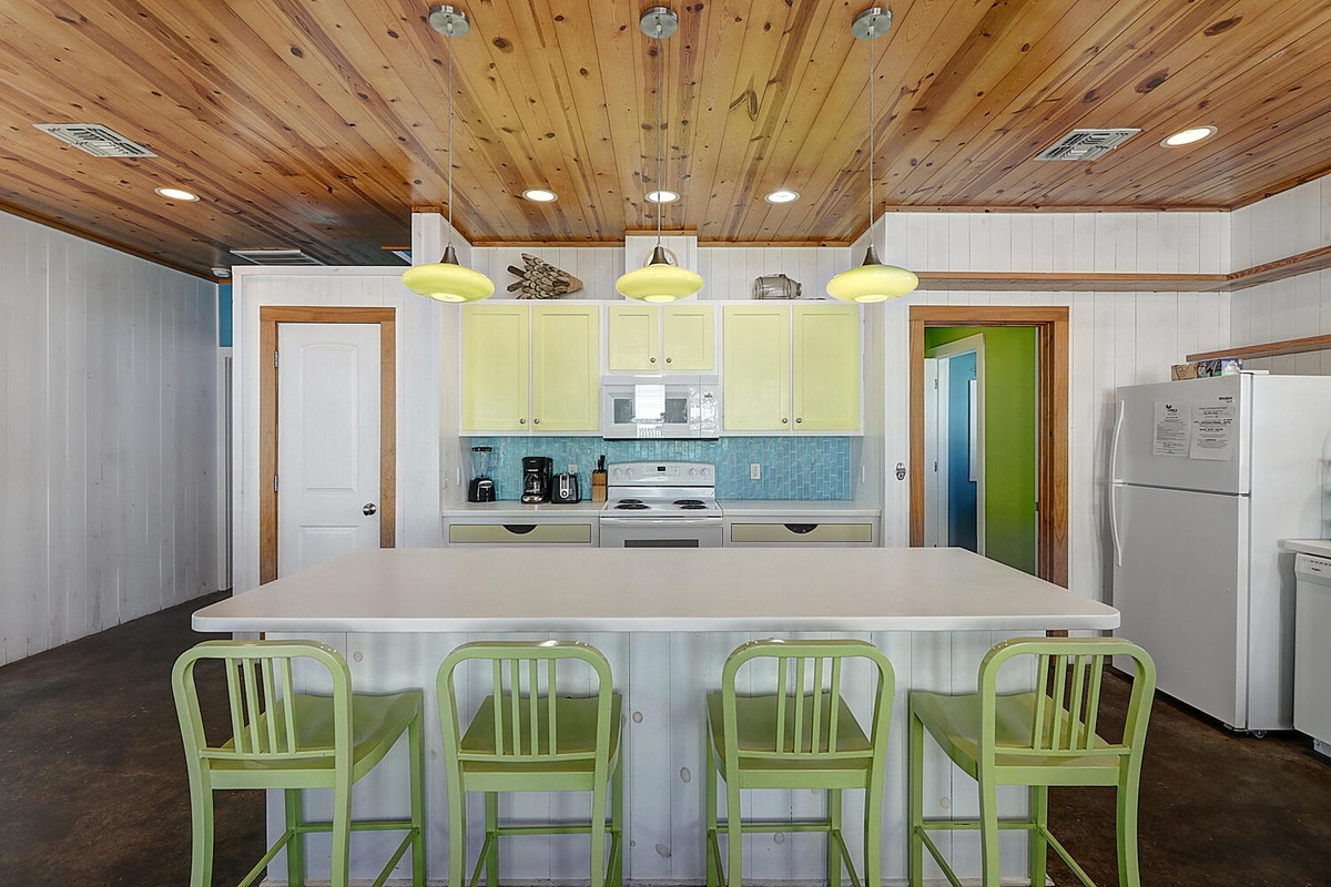 Your coastal kitchen awaits with charming lime accents and warm wood ceilings.