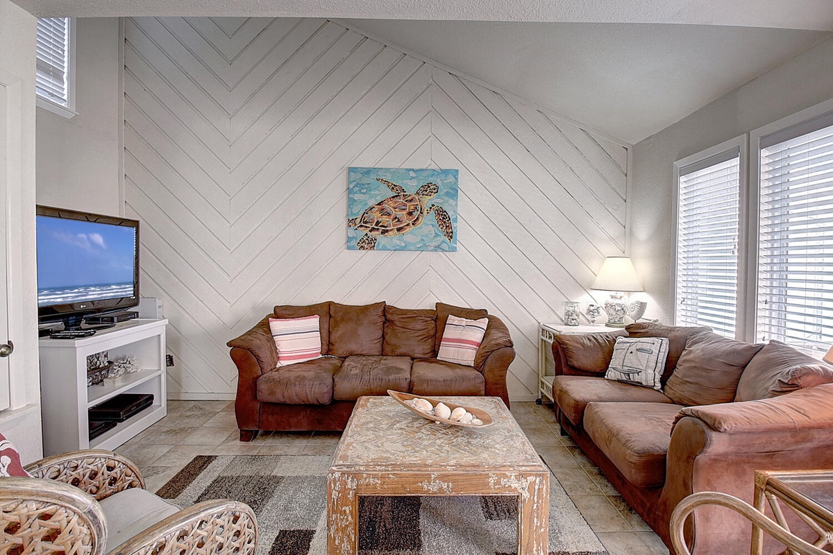 Sink into plush leather sofas beneath coastal artwork in your spacious living room, perfect for movie nights or beachside relaxation.