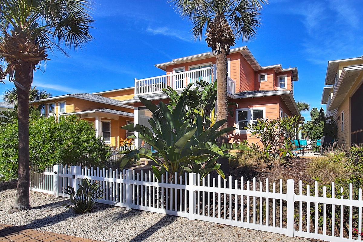 Charming beach houses with tropical landscaping nestled in a peaceful coastal neighborhood under clear blue skies.