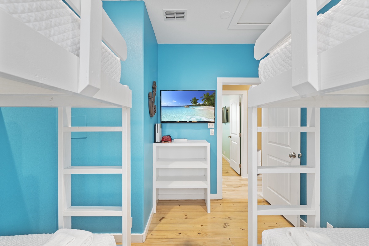 Cheerful turquoise walls and crisp white built-in bunk beds create a bright, coastal retreat for your group. Nautical charm meets modern comfort in this inviting space.