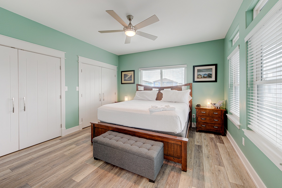 Drift off to sleep in this tranquil bedroom with soothing mint walls, crisp linens, and gentle ceiling fan creating your perfect sanctuary.